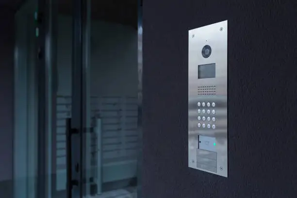 Photo of Entrance doorbell in a multi-apartment building, with a video surveillance camera, on a dark wall