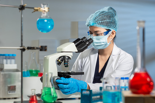 Shot of a young scientist using a microscope while conducting research in a laboratory