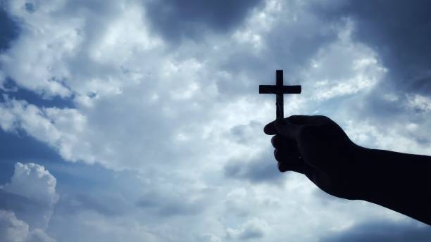 istock Christianity concept - hand holding a Cross with sky background. 1365131311