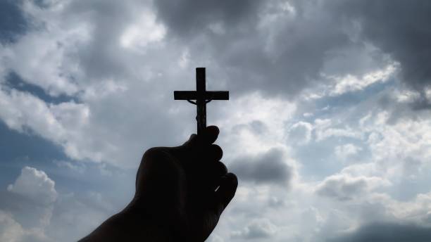 istock Christianity concept - hand holding a Cross with sky background. 1365131404