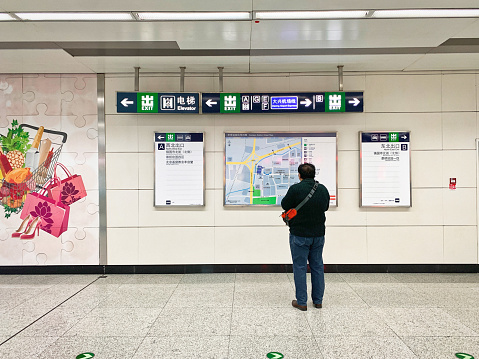October 23, 2021: Beijing Subway Line 10 CAOQIAO Station Hall, a male passenger looks at the information Guide.