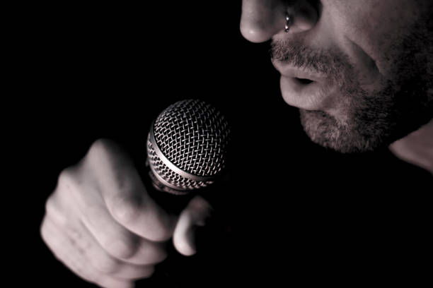 istock Singer man with round microphone on dark background 1365134244