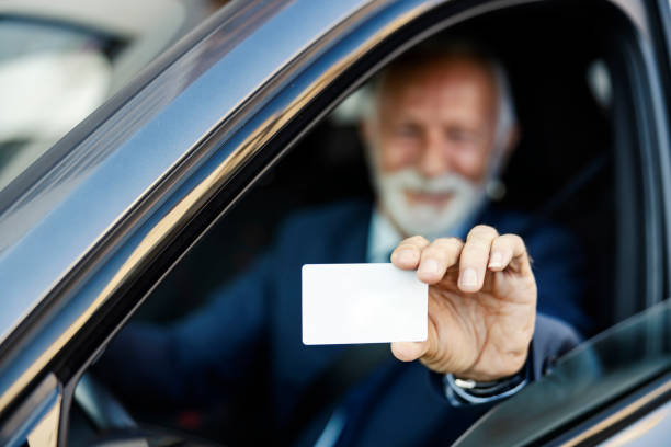 serviço de estacionamento cartão pré-pago. feche acima de um homem de negócios sênior sentado em seu carro e mostrando seu cartão de serviço de estacionamento através da janela. foco seletivo na mão. - prepaid card - fotografias e filmes do acervo