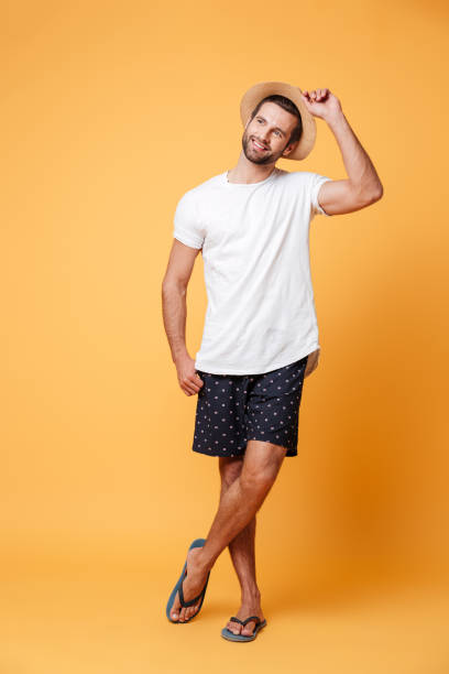 istock Attractive man wearing flip flops and hat looking away isolated 1365135409