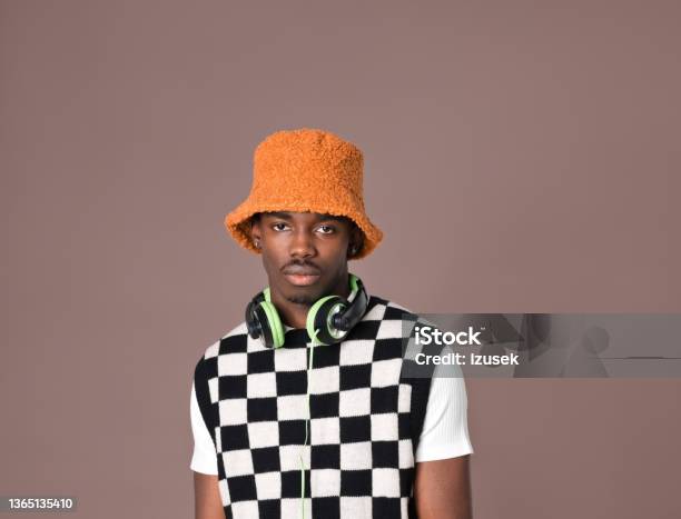 Confident Young Man Against Brown Background Stock Photo - Download Image Now - Bucket Hat, Orange Color, Headphones