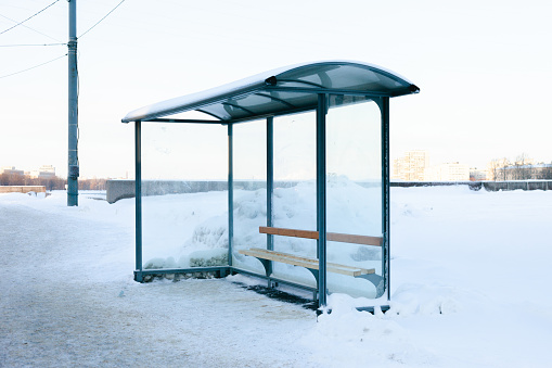 Snow-covered bus stop on a deserted winter street. Sunny weather, frost, authentic photo