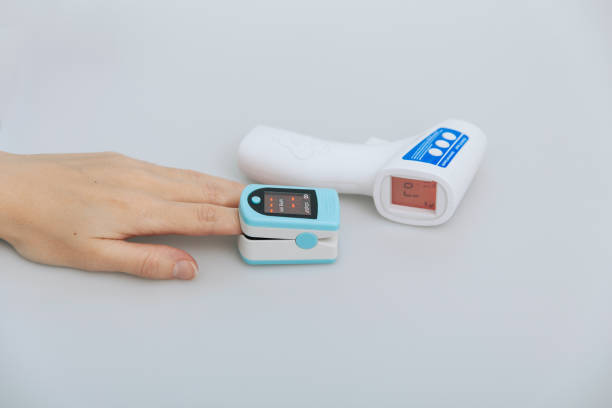 istock Pulse oximeter and thermometer gun on white background. Measuring oxygen saturation, pulse rate and oxygen levels. Infrared isometric thermometer gun to check body temperature for virus symptoms 1365136802
