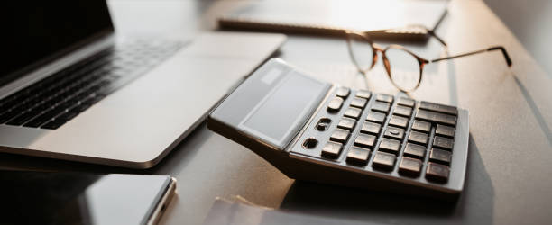 istock Place of work in office, calculator, laptop computer, glasses at office desk 1365137429