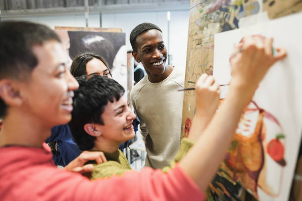 Multiracial students painting inside art room class at university - Focus on african man face stock photo