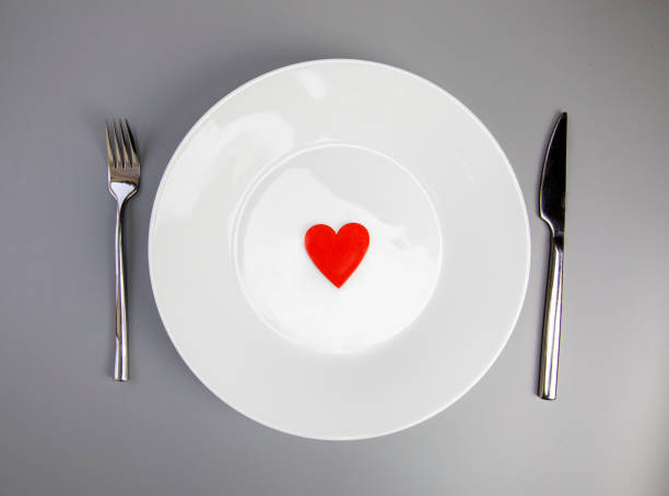 istock White plate with, fork and knife, red heart on grey background, flat lay. Valentine's day or medical health concept top view 1365137629
