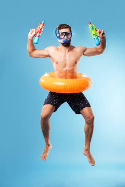 istock Young man jumping wearing swimming circle and glasses 1365138238
