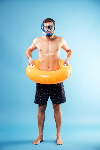 istock Young man holding swimming circle while standing isolated 1365138271