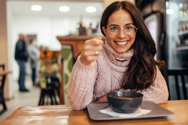 Happy caucasian woman, ordering a bowl of soup in a restaurant.
