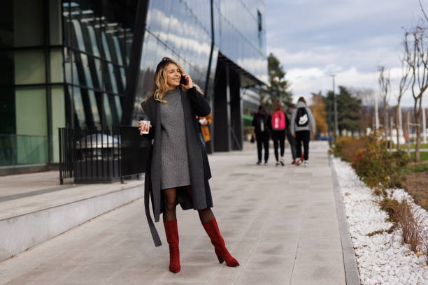 istock Smiling businesswoman using phone in front of office building 1365139629