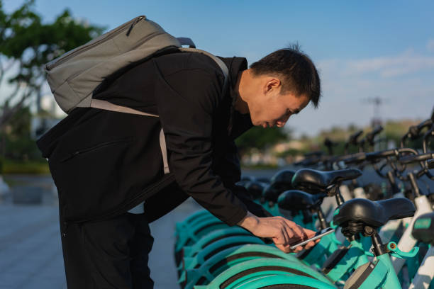 Asian man uses mobile phone to scan QR code to unlock shared bike Man uses phone app to unlock shared bike bike rentals stock pictures, royalty-free photos & images