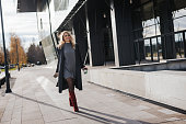 Young business woman walking with take away paper cup outdoors