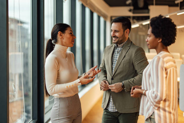 istock Three elegant office workers, attending an office party in the company building. 1365141207