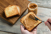 Female hands spread peanut butter on toast close-up.