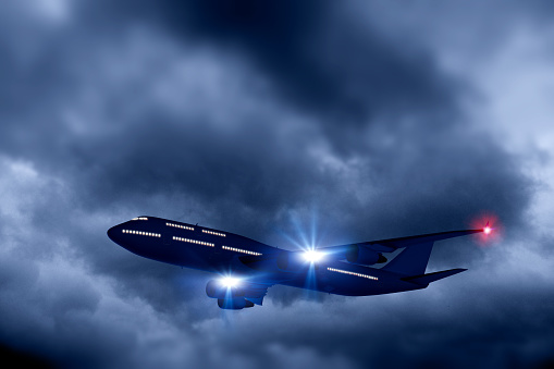 Passenger jetliner flying amid dark clouds with evening light conditions. Airplane cabin windows are illuminated, while landing and position lights are on. Composite image with digitally generated models. Copy space.