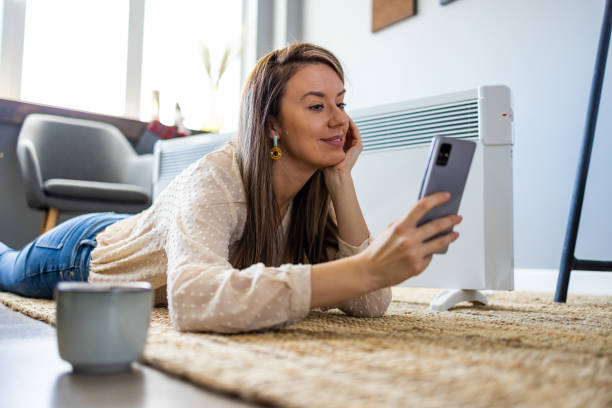 istock Woman and radiator using smartphone app for temperature control 1365146745
