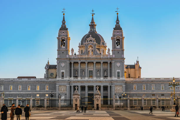 People on Plaza de la Armeria Square in front of the Almudena Cathedral in the evening light in Madrid stock photo