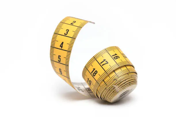 Close up of yellow white rolled up tape measure for tailoring measurement on white background