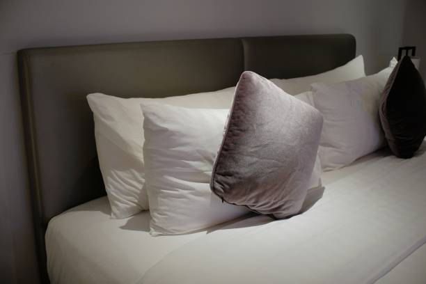 istock Comfortable bed and fluffy with piles of pillows and dim lighting 1365150715