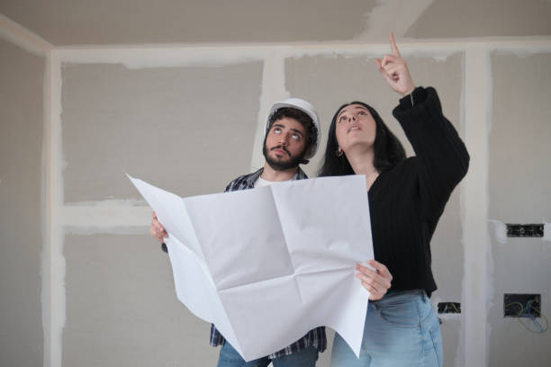 istock Young woman asking to the architect about the ceiling in a construction house. 1365150807