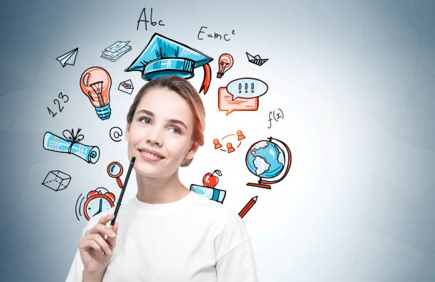 Portrait of pensive young woman with pencil standing near gray wall with creative education sketch drawn on it
