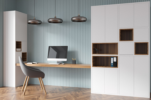 Home office interior design with white minimalist cabinet, green wall panels, three metallic lamps over niche desk, comfortable chair and parquet floor. Concept of modern workspace. 3d rendering