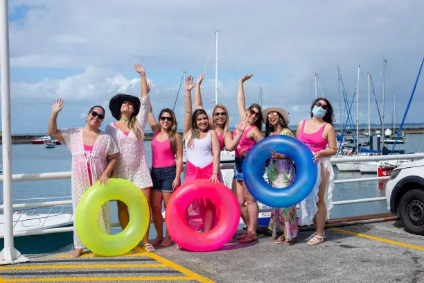 Photo of Women standing with their arms up in a bikini with beach accessories.