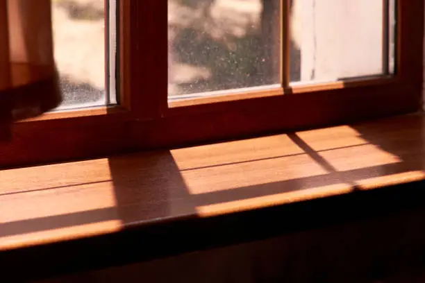 sunlight shining through the window and shadows on the wooden windowsill