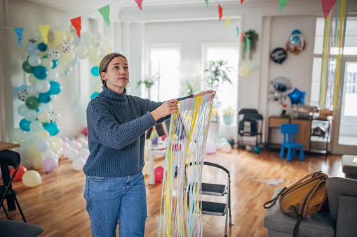 Young woman decorating room for birthday party