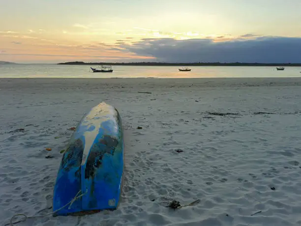 Caiçara canoe on the sand of a beach in front of the bay of Paranaguá at dusk