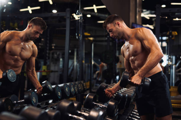 istock Determined young man lifting up dumbbells in the gym 1365159562