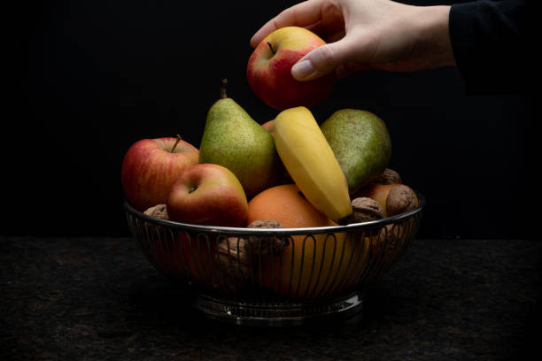 frutero y una mano de mujer tomando una manzana - tazón para frutas fotografías e imágenes de stock