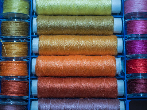 A lot of sewing colored thread. Thread reels. Colorful threads in the box. Texture of sewing accessories