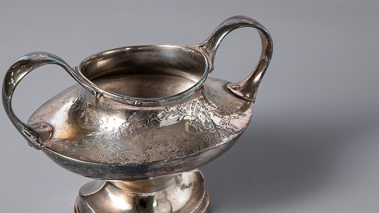 Isolated antique silver sugar bowl on a gray background.  Beautiful silverware close up.