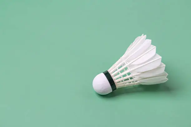 Photo of Shuttlecock badminton on green background with copy space