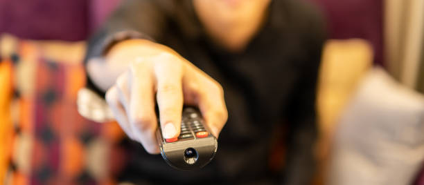 Male hand holding remote controller while watching TV stock photo
