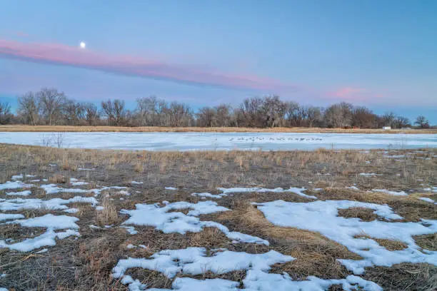 dusk over Colorado plains with a frozen lake and abandoned farm