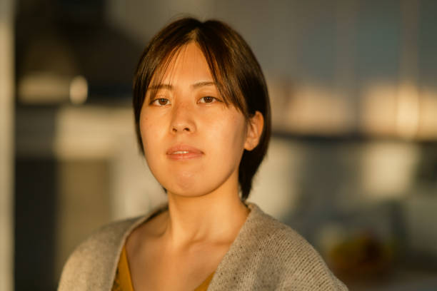 istock Beautiful young woman using smart phone and relaxing in kitchen during sunset 1365170279