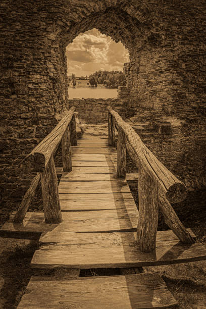 Koknese Castle is a complex in Koknese, Latvia, dating from the 13th century. Wooden bridge to old ruined window. Monochrome, sepia.