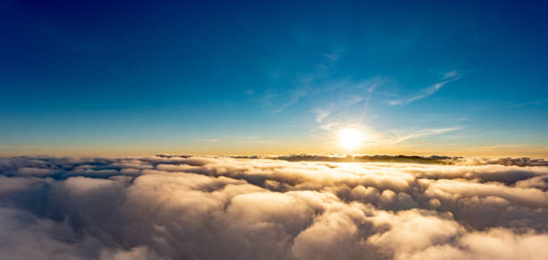 istock Sun shining brightly above white fluffy clouds at sunrise 1365172515
