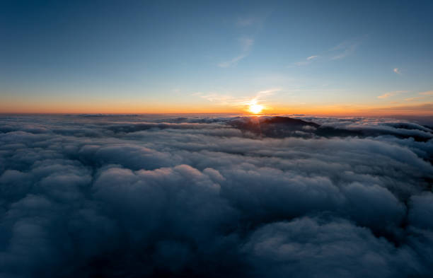 istock Sun shining brightly above white fluffy clouds at sunrise 1365172584