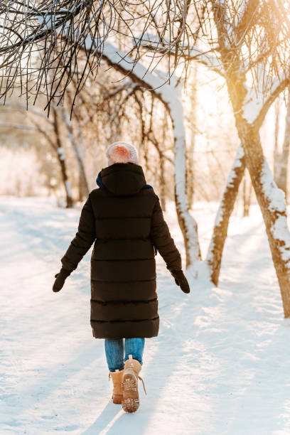 istock A young beautiful woman walks on a path in a snowy winter forest 1365172659