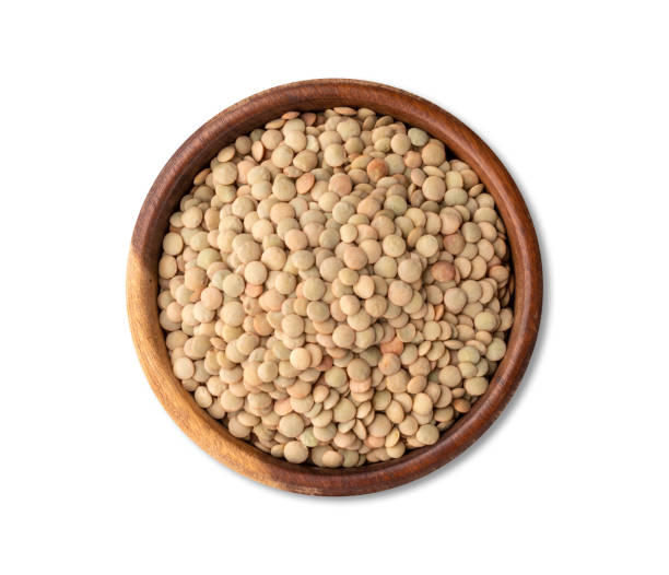 istock Raw lentils in a wooden bowl isolated over white background 1365173393