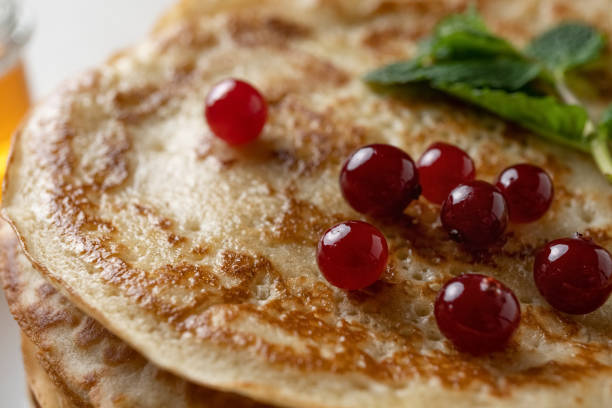 Close-up plan of thin pancakes for Shrovetide with honey and cranberries