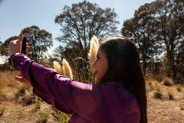 istock woman taking a selfie with her cell phone in Mexico state surrounded by fox tail and grass Polypogon monspeliensis outdoors freedom lifestyles 1365177121