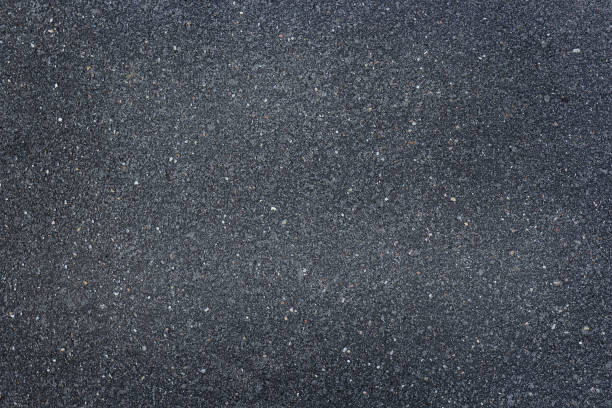 istock Smooth dark gray asphalt pavement texture with small stones 1365177673